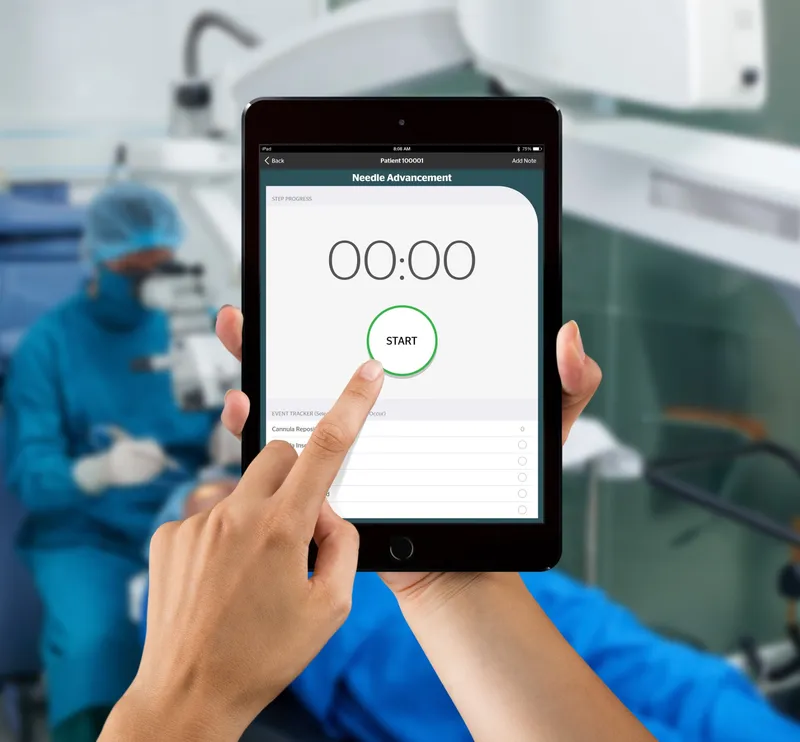Hands holding an iPad showing a step timer with a Start button, in front of a blurred operating room